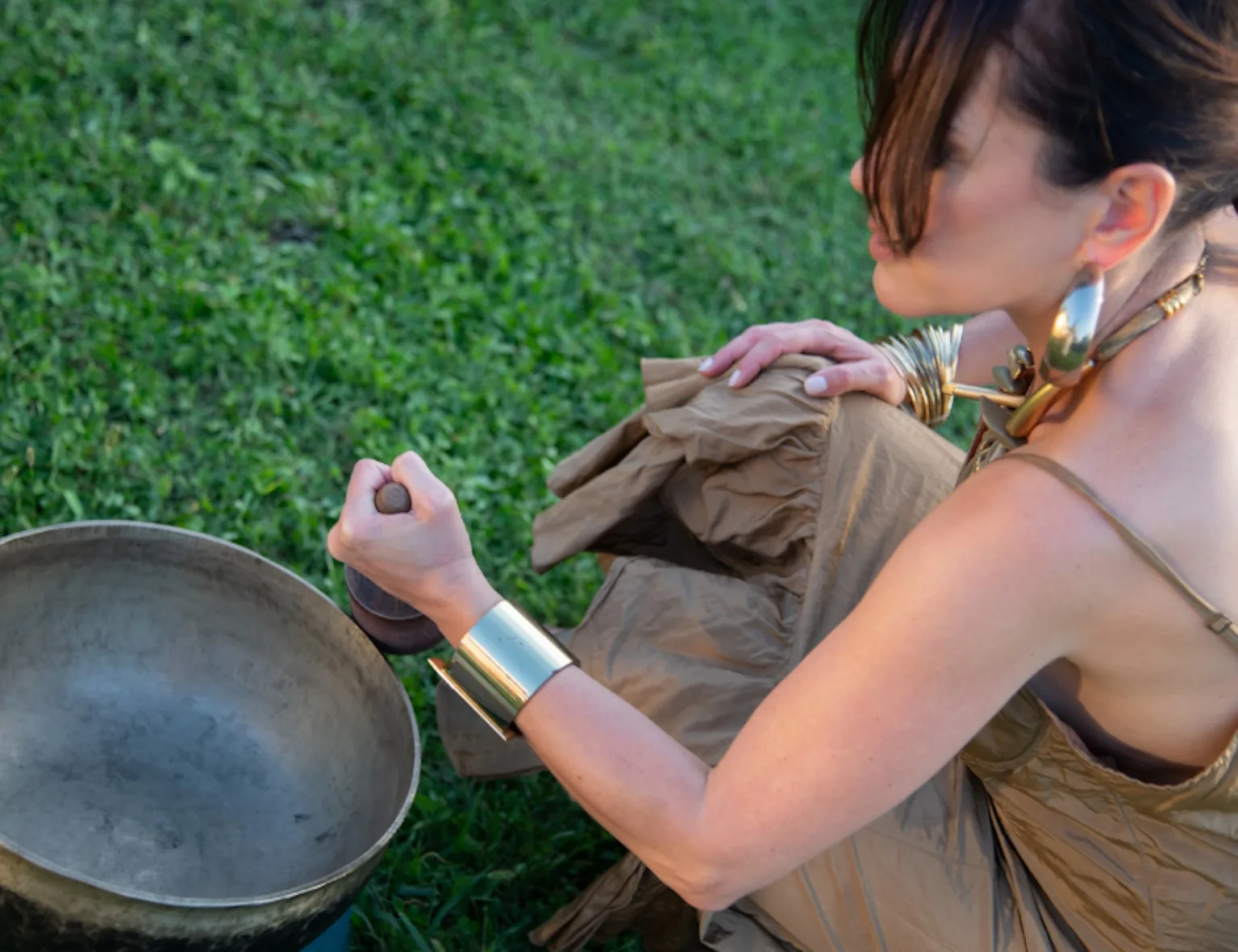 Psicoterapeuta transpersonale che suona la campana tibetana su un prato 